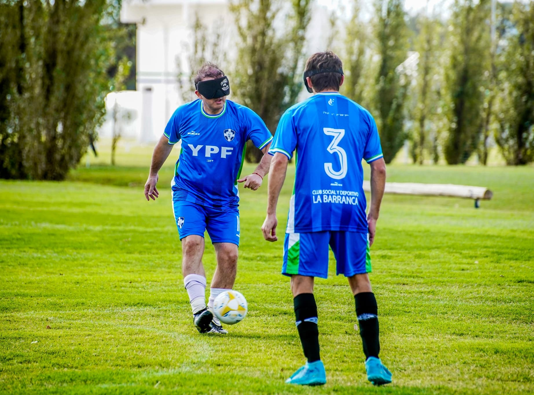 Dos jugadores de fútbol para ciegos disputan la pelota, uno con el antifaz reglamentario puesto.