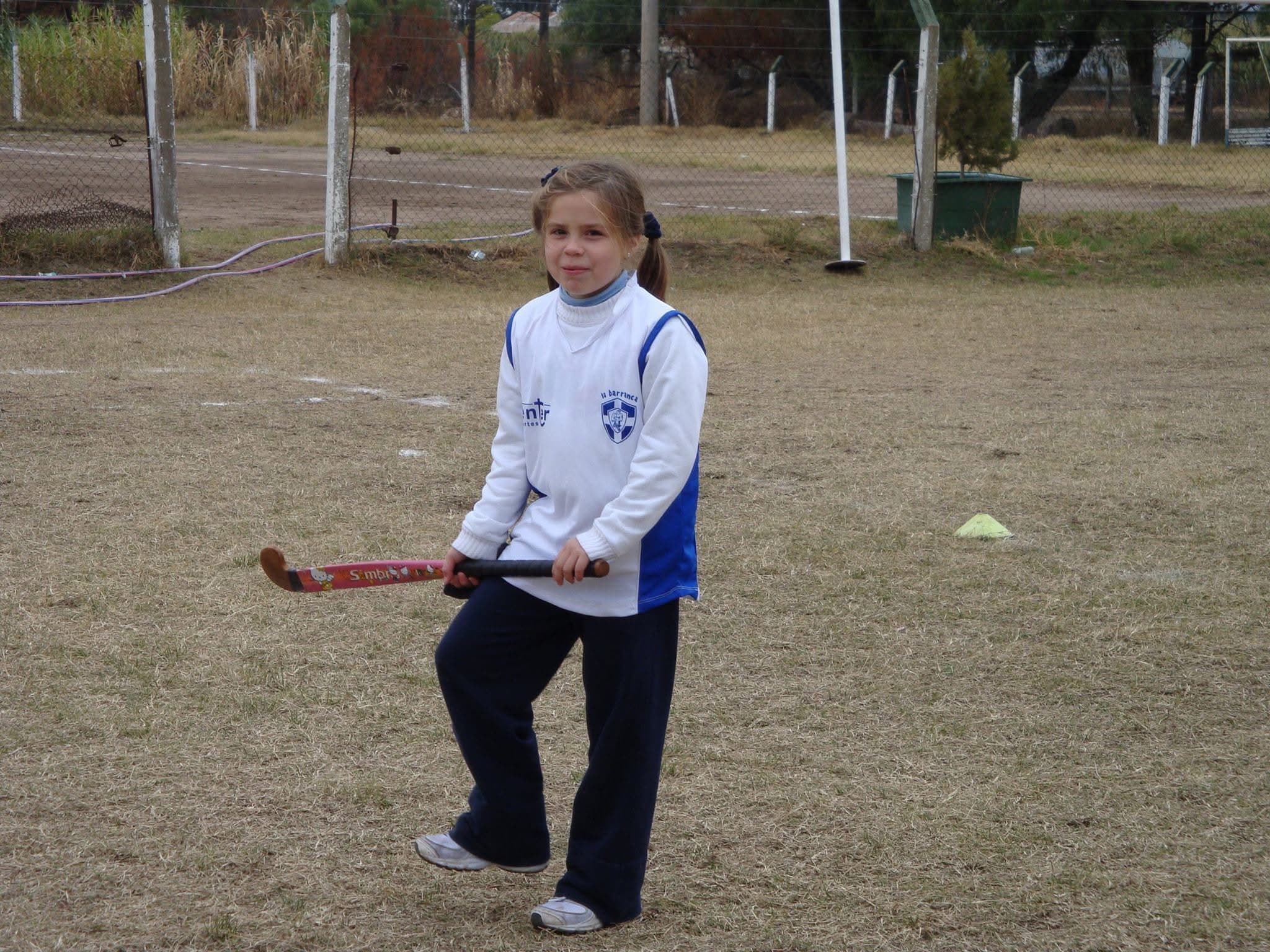 Una jugadora de la escuelita practica con el palo en la cancha del club.